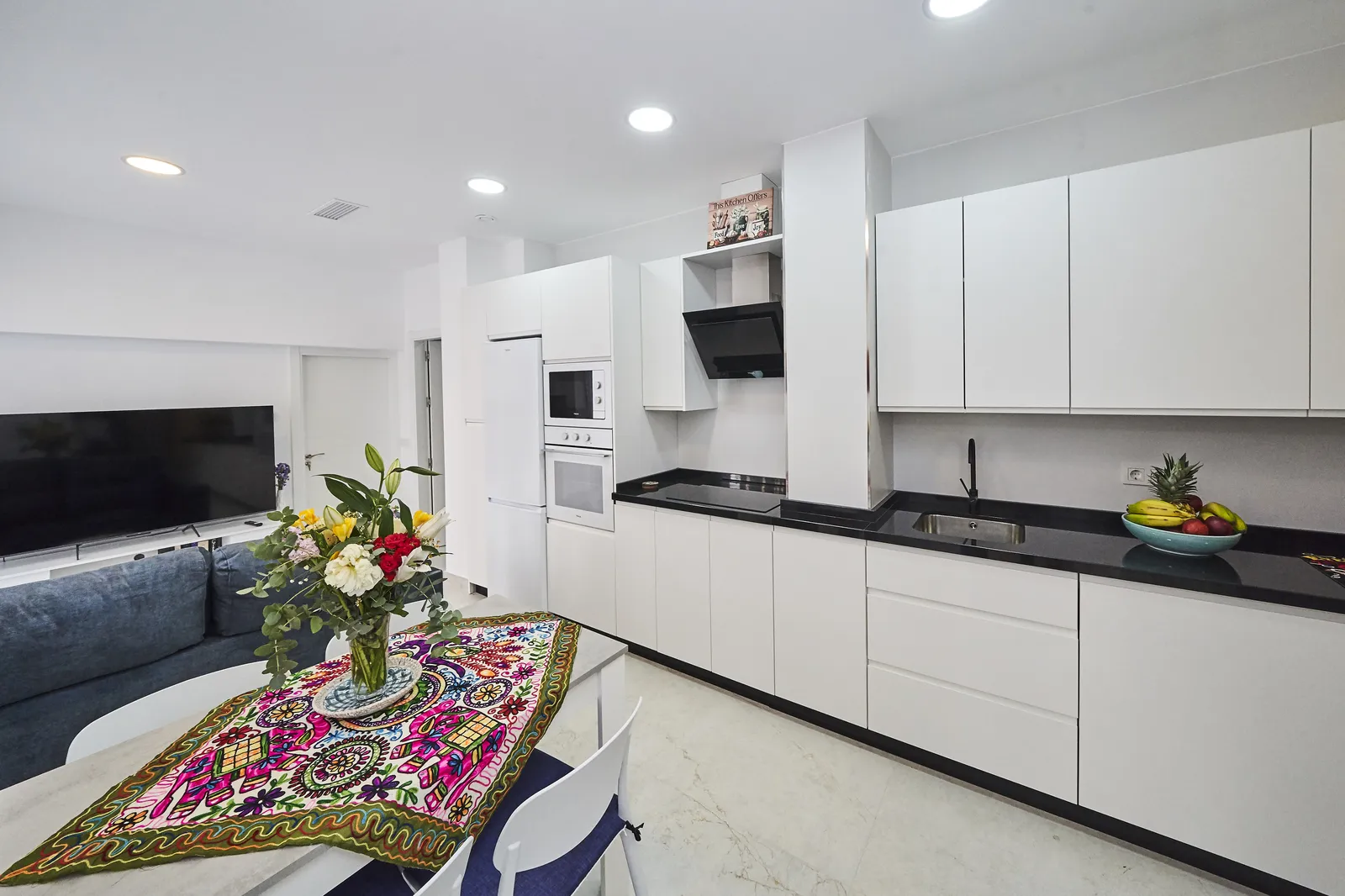 Salón-comedor con cocina abierta y flores en Casa Isolde, Nerja